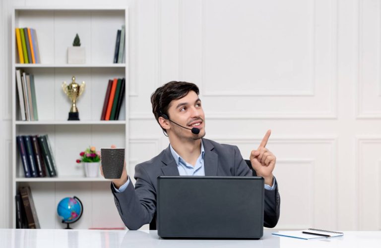 a man sitting at a desk with a microphone and a cup